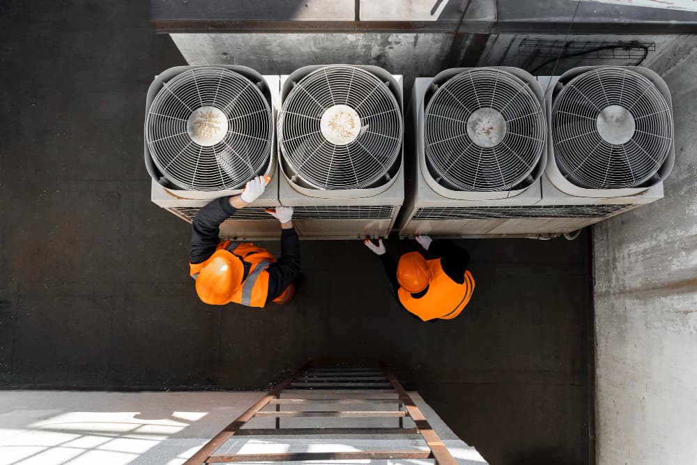 Overhead view of technicians inspecting commercial HVAC units, indicating a possible "HVAC System Struggling"