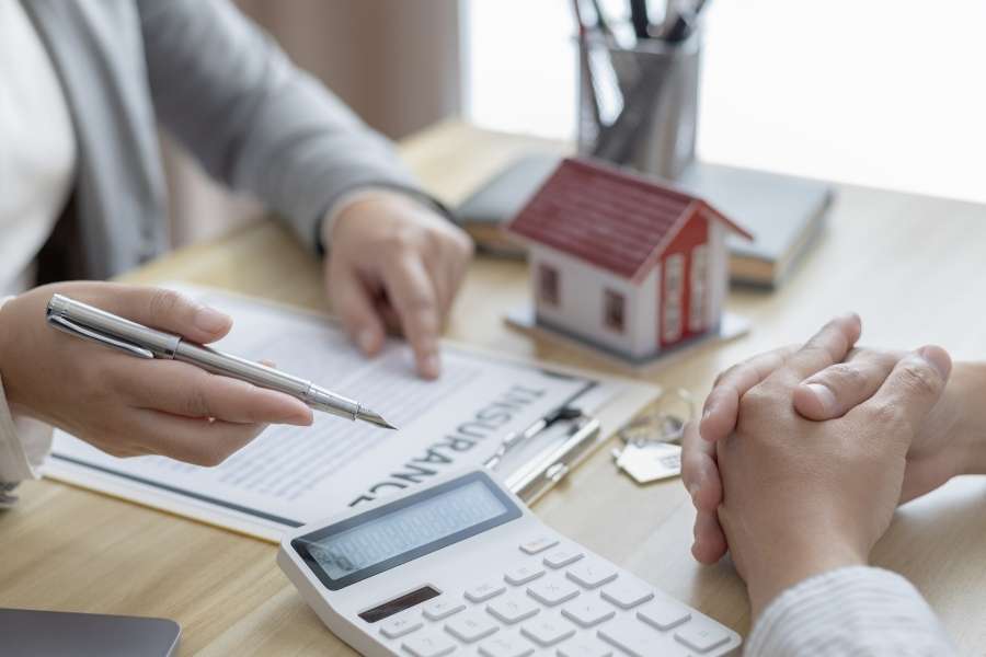A professional pointing at insurance documents on a desk to boost your property value.