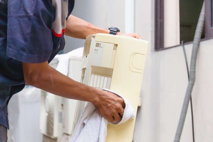 A technician wiping down components during an AC replacement project.