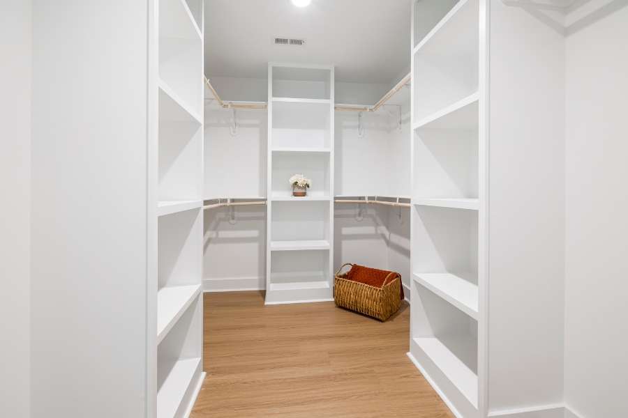 A modern walk-in closet featuring custom white shelving and clever storage solutions.
