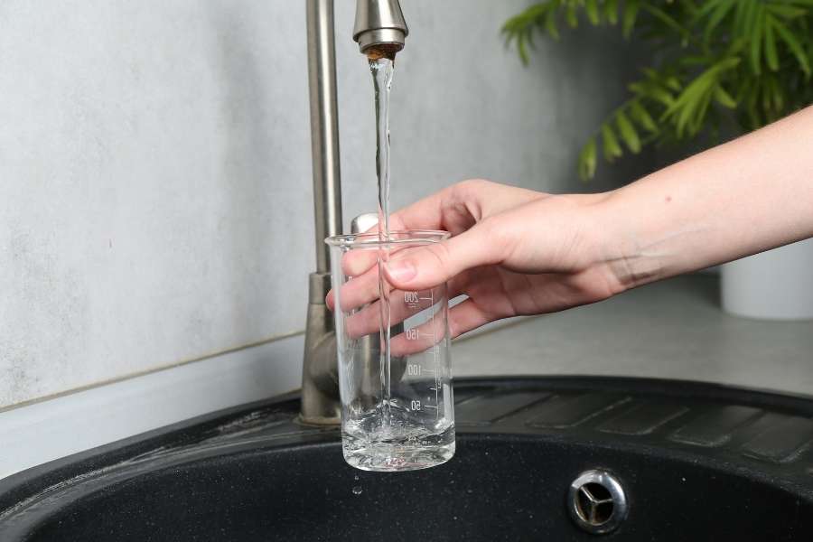 Water flowing from a kitchen tap into a glass, illustrating low water pressure issues.