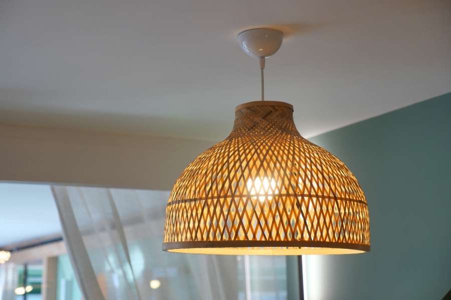 Woven rattan hanging light suspended from a white ceiling.